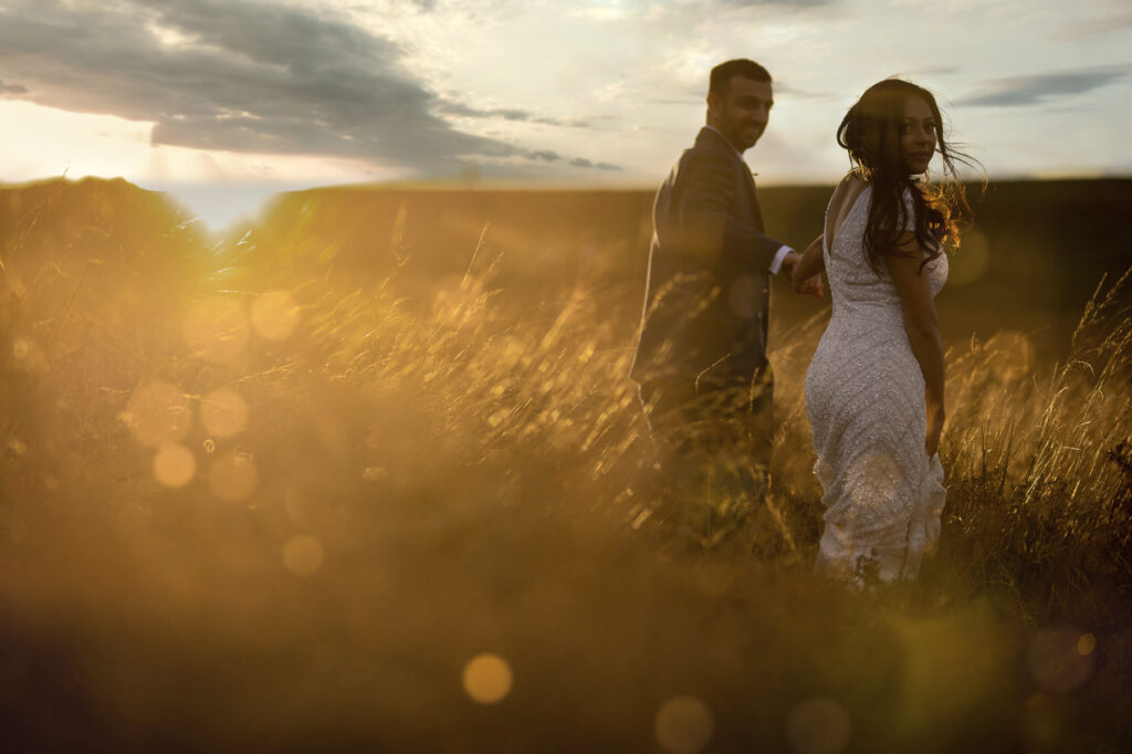 Wedding couple in field at sunset