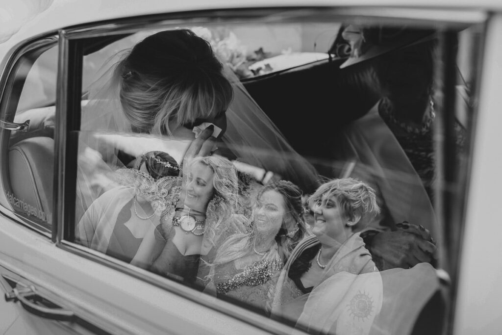 Bride crying with reflection of bridesmaids in window